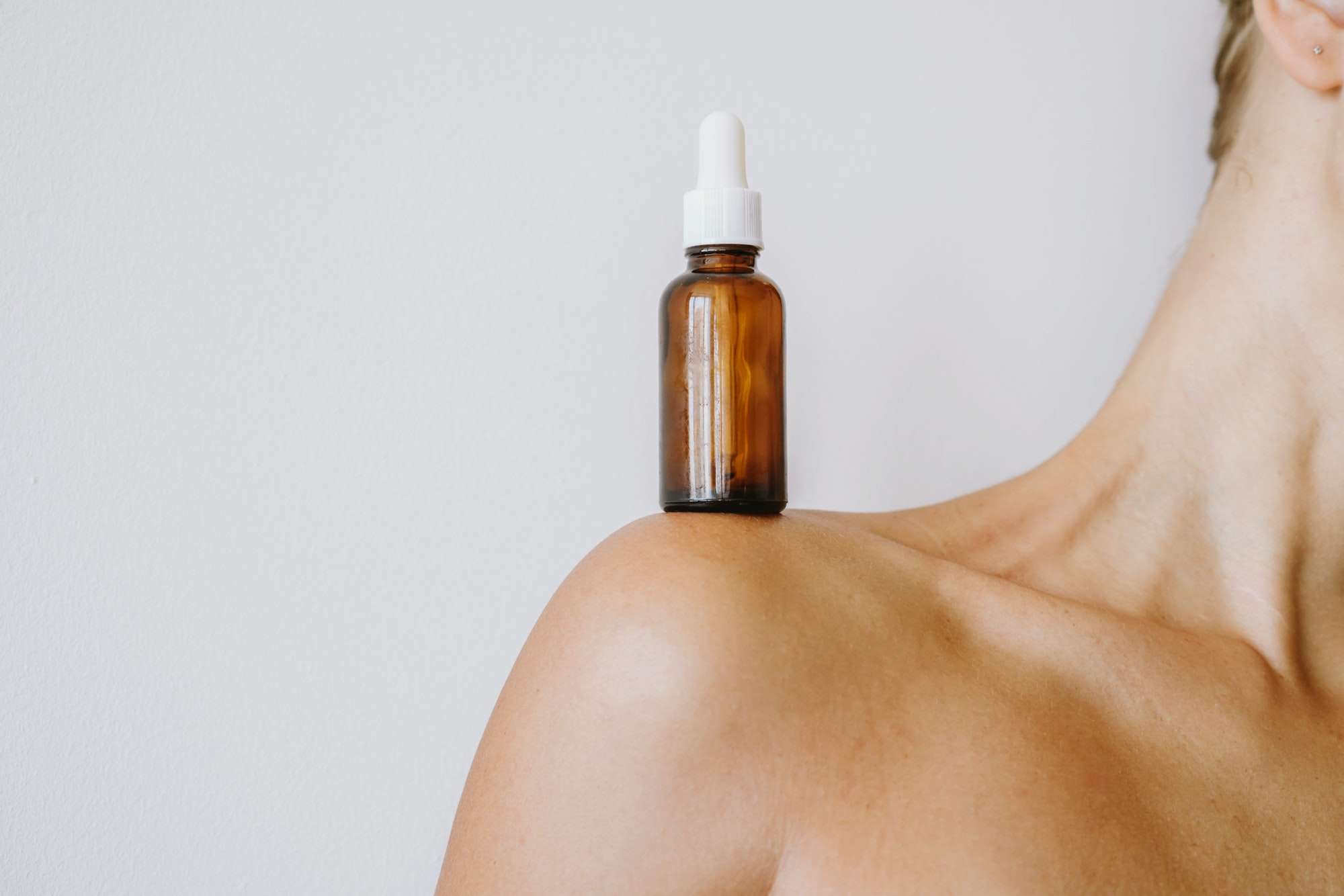 Woman with the serum bottle on her shoulder